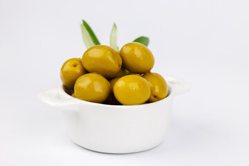 Healthy food concept with green olives in bowl and olive branch on white table