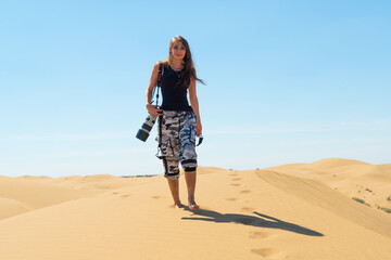 Photographer walking on top of a dune in Kyzylkum Desert with camera in hand