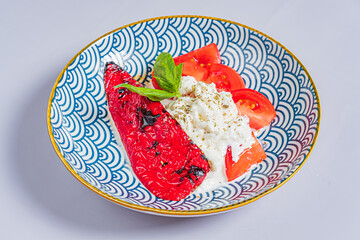Vibrant plate features roasted red pepper, creamy burrata, and juicy tomato slices with herbs