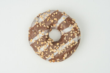 Close-up image of a chocolate-glazed doughnut with nut sprinkles Brown color palette, blurred background, and simple food photography style
