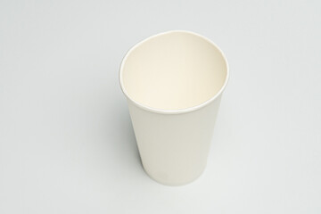 White single-serving beverage cup with two-tone appearance darker rim and base on a light gray...