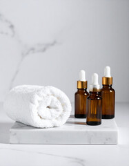 A white fluffy towel folded on a marble platform next to bottles of calming essential oils.