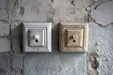 light switches on a white wall, flipped up and flipped down, casting shadow.