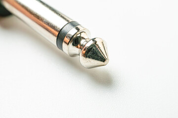 A high-resolution photo of a metallic pen, showcasing sleek design and shiny finish The pen, possibly stainless steel, has a clip for easy access It rests on a light gray surface, emphasizing its r