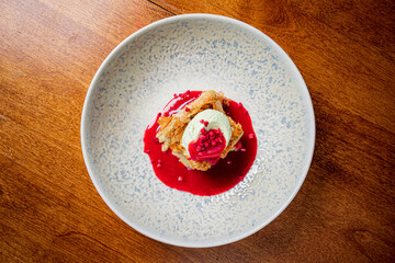 A crispy pastry topped with mint ice cream, raspberry sauce, and fresh fruit