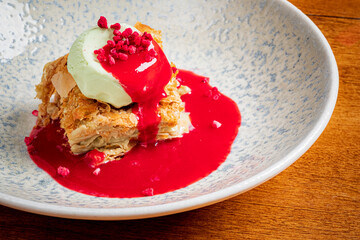 Layered pastry topped with mint ice cream and raspberry sauce creates a vibrant dessert experience