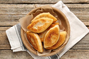 Delicious fried pyrizhky (stuffed pies) on wooden table, top view