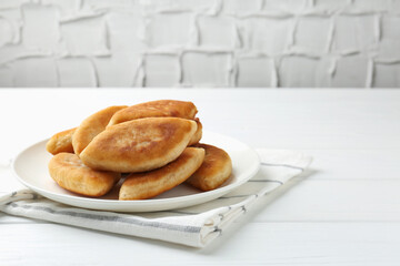 Delicious fried pyrizhky (stuffed pies) on white wooden table, closeup. Space for text