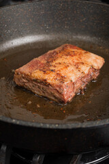 A succulent piece of meat sizzles in a hot frying pan, releasing savory aromas as it cooks