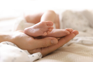 Mother with her little baby on bed indoors, closeup