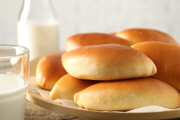 Tasty baked patties and milk on wooden table, closeup