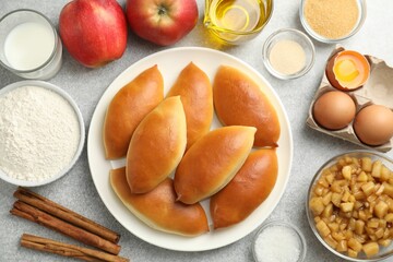 Tasty baked patties and ingredients on light grey table, flat lay