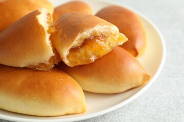 Tasty baked patties with orange jam on light grey table, closeup