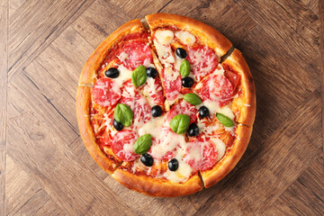 Tasty pizza with salami, cheese, basil and olives on wooden table, top view