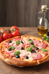 Tasty pizza and ingredients on wooden table, closeup
