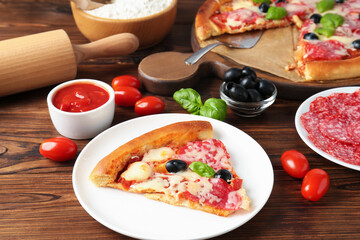 Tasty pizza and ingredients on wooden table, closeup