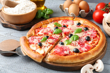 Tasty pizza and ingredients on grey wooden table, closeup