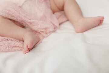 Cute little baby lying on bed at home, closeup. Space for text