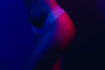 Obraz premium Colorful neon light highlights the graceful form of a young woman wearing underwear in a stylish artistic composition.