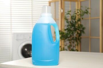 Bottle of fabric softener on wooden table indoors