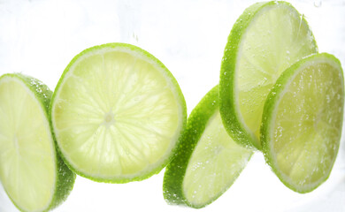 Refreshing soda water with slices of lime in glass on white background, closeup