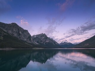 Fototapeta premium A calm lake reflecting mountain peaks under a twilight sky, Ai Generate.