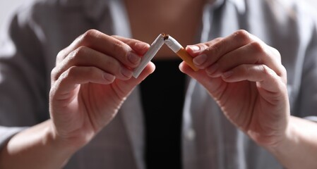 Woman holding broken cigarette, closeup. Stop smoking