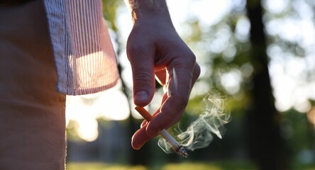 Man with cigarette in park, closeup. Space for text