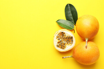Ripe passion fruits and leaves on yellow background, flat lay. Space for text
