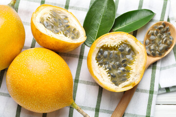 Ripe passion fruits, green leaves and seeds on table, flat lay
