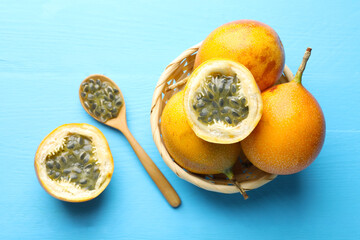 Ripe passion fruits and seeds on light blue wooden table, flat lay