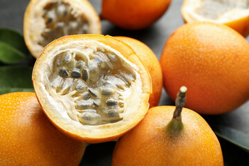 Ripe passion fruits and green leaves on table, closeup