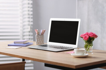 Workplace with laptop and beautiful flowers in office