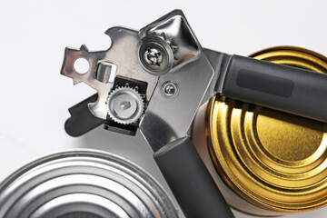 Can opener and tins on white table, flat lay