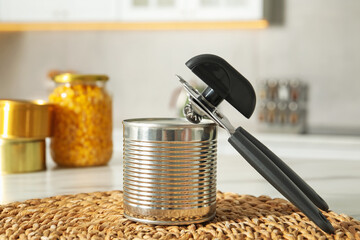 Can opener and tin on white table indoors, closeup