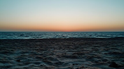Obraz premium Tranquil Sunset at Ocean Shore with Calm Waves and Warm Sky Colors Reflecting Nature's Beauty