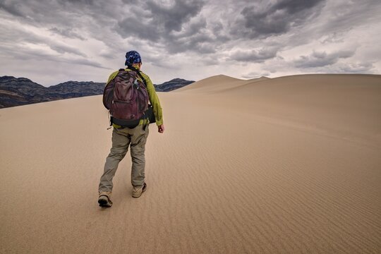 Rear view of a Man walking across Eureka Sand Dunes, Death Valley National Park, California, USA
