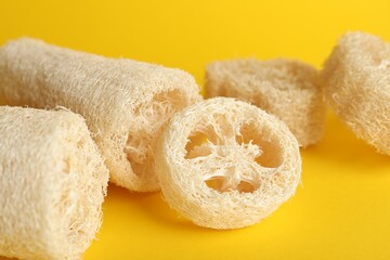Natural loofah sponges on yellow background, closeup