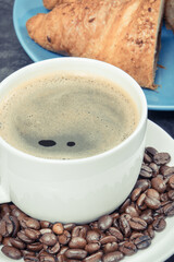 White cup of coffee and fresh croissant with chocolate