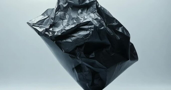A crumpled black plastic bag rotates slowly against a light gray backdrop.