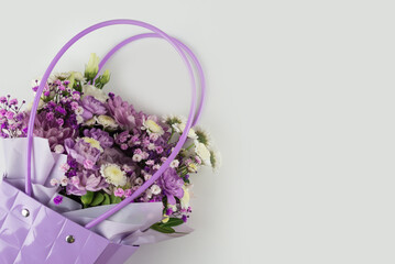 Bouquet of different purple flowers in a gift bag on a white background. Gift for a holiday, Women's Day, Wedding.
