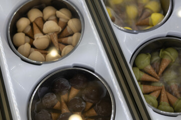 Delicious ice cream cones in various flavors, displayed in a refrigerated case. Perfect for summer treats!