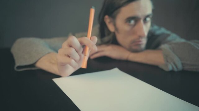 Contemplative Scene of a Young Adult Struggling with Creativity at a Table, Hovering Over Blank Paper with Orange Pen