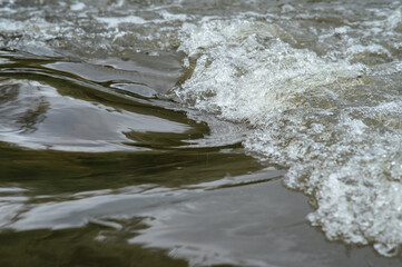 Detailed view of dynamic water surface with natural ripples, foam, and reflections. Capturing...