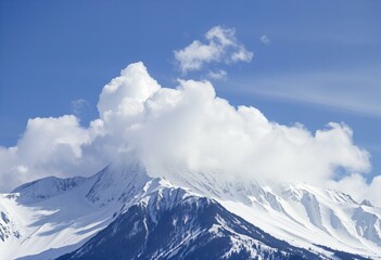 Photo Clouds cover a snow-capped mountain peak.