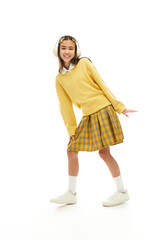 Stylish schoolgirl poses joyfully in a studio wearing a trendy uniform outfit