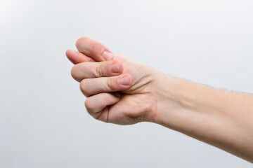 Hand making a fig sign gesture against a plain background.