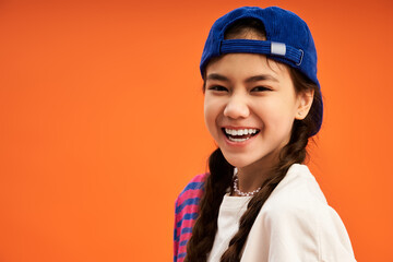 Stylish teen girl poses confidently against a bright orange studio backdrop