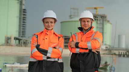 caucasian white engineers in safety uniforms and helmets using laptop and radio for site communication. Concept of teamwork, inspection, and operations at an industrial facility.Construction of Oil, 