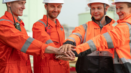 caucasian white engineers in safety uniforms and helmets using laptop and radio for site communication. Concept of teamwork, inspection, and operations at an industrial facility.Construction of Oil,